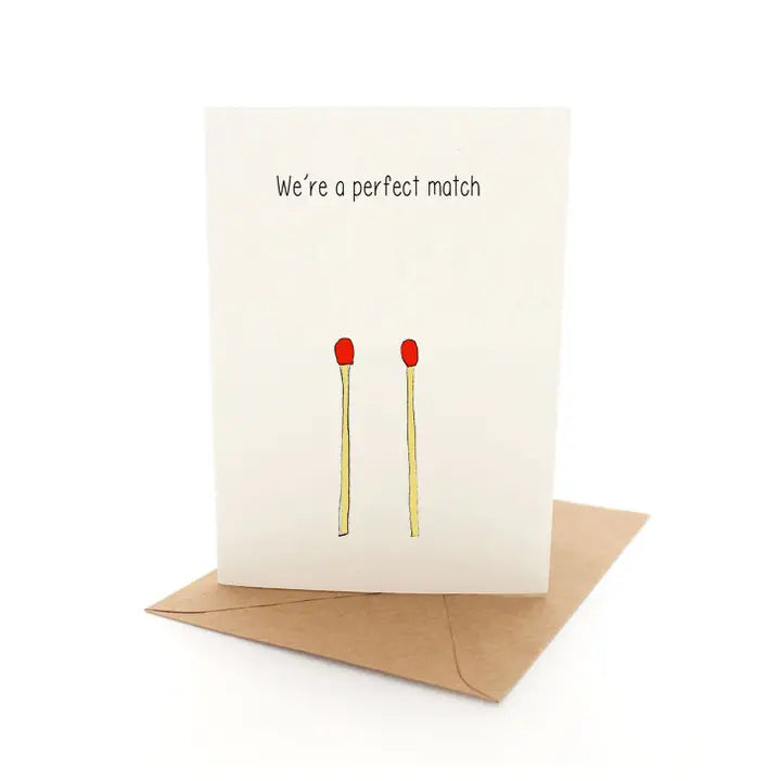 A greeting card with a white background, featuring a cartoon illustration of two red candles and the text 'We're a perfect match' in bold black letters.