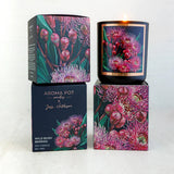 A scented candle with artwork of wild bush berries on the packaging, alongside its box which has the product name and artist's signature.