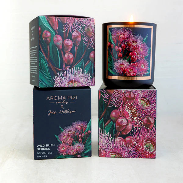 A scented candle with artwork of wild bush berries on the packaging, alongside its box which has the product name and artist's signature.