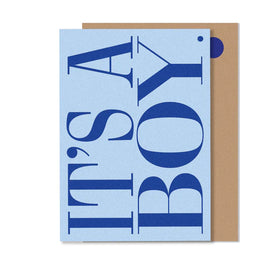 A greeting card with 'It's a BOY' text in blue uppercase letters, accompanied by a beige envelope.