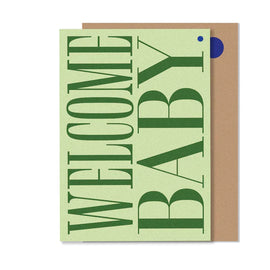 A greeting card with 'Welcome Baby' text in green on a beige background, with a small blue dot and a envelope.