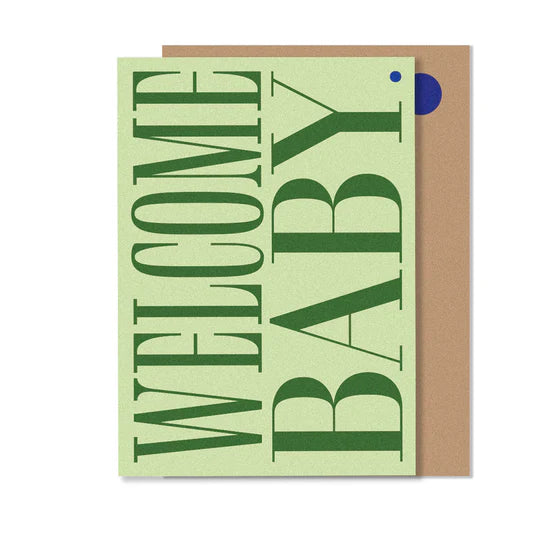 A greeting card with 'Welcome Baby' text in green on a beige background, with a small blue dot and a envelope.