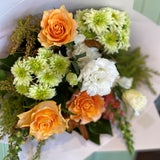 Close up of flowers in orange, green and white with sprigs of foliage
