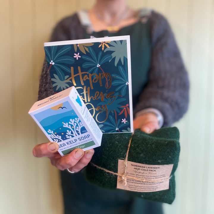 Person holding a box of soap, a bag of felt, and a card with 'Happy Father's Day' text.