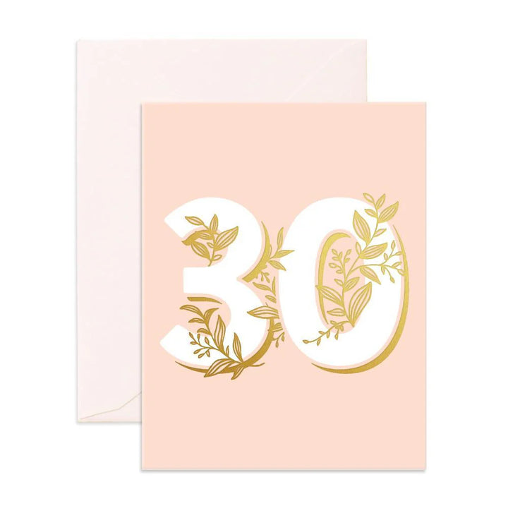 A greeting card with a pink background and the number 30 written in gold, surrounded by green leaves.