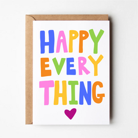 A colorful greeting card with the text 'HAPPY EVERYTHING' on it, placed on a card holder.