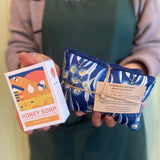 Person holding a bar of soap and a bag with a visible brand name.