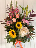 Bouquet of flowers with sunflowers, pink tulips, and other assorted flowers on a white background
