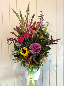 Bouquet of flowers with pink and yellow flowers in a clear vase against a light background