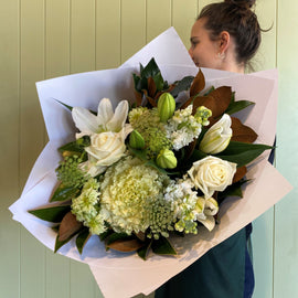 Person holding a bouquet of white flowers against a light green wall