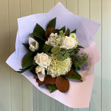 Bouquet of white and green flowers wrapped in paper against a wooden background