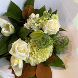 Bouquet of white and green flowers with leaves on a light background
