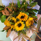 Smellies Flowers' SUNFLOWERS bouquet features vibrant yellow blooms and lush foliage, wrapped in white paper and held by someone in a black top, showcasing sustainable floristry with Australian-sourced flowers.
