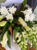 Close up photo of white flowers that include snapdragons, lilies and chrysanthemums