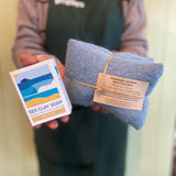 Person holding a bar of sea clay soap and a blue pouch with a label.
