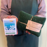 Person holding a bar of sea kelp soap and a green towel with a label.