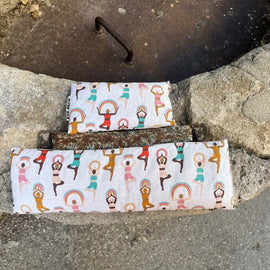 Two fabric wraps with yoga pose design on a stone surface