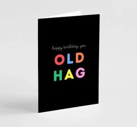 A greeting card with 'Happy birthday, you OLD HAG' written in colorful letters on a black background.