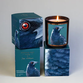 Candle with magpie bird design packaging on a white background