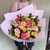 A woman stands gracefully, holding a vibrant bouquet of flowers, showcasing her joy and appreciation for nature's beauty.