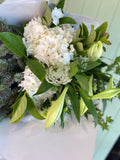 White and green flowers including Christmas lillies wrapped in white paper