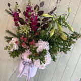White vase of flowers with a white vase against a light wooden panel background