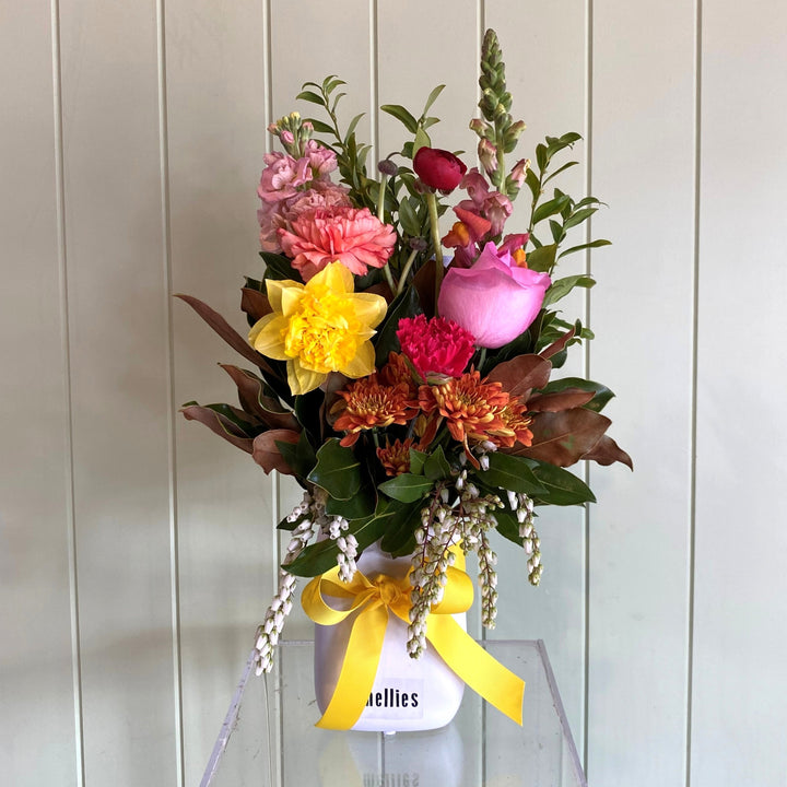Colorful flower bouquet i a vasewith a yellow ribbon on a white background