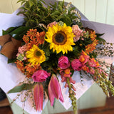 Bouquet of flowers with sunflowers and pink roses on a wooden surface.