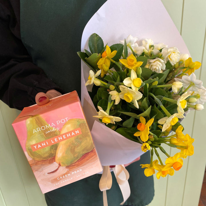 Person holding a bouquet of flowers and an Aroma Bot with 'Yani Leneman' branding.