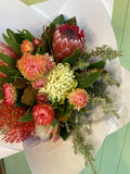 Bouquet of colorful flowers including proteas and other varieties on a light background.