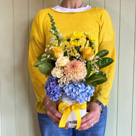 Person holding a bouquet of flowers against a wooden wall