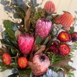 Bouquet of pink and orange flowers with green leaves on a white surface