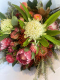 Bouquet of colorful flowers including proteas and banksia on a light background