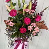 Bouquet of pink and purple flowers with a pink ribbon on a white background