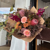 Bouquet of native flowers in tones of peach, rust and burgundy with brown paper wrap