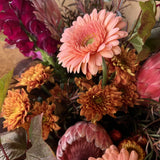 Bouquet of native flowers in tones of peach, rust and burgundy with brown paper wrap