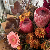 Bouquet of pink and orange flowers with green and autumn leaves