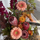Arrangement of flowers with pink, orange, and burgundy colours