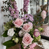 Arrangement of soft pink, mauve and white flowers with a decorative ribbon