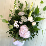 Large floral design of white flowers including hydrangeas, chrysanthemums, roses, lilies, Queen Annes lace and snapdragons.
