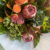 Close up of proteas, strawflowers and other textured flowers wrapped in white paper