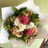 Bouquet of flowers wrapped in white paper on a light green background