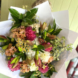 Bouquet of flowers wrapped in white paper held by a person.
