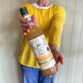 Person holding a bottle of 'Pina Colada' against a white wall