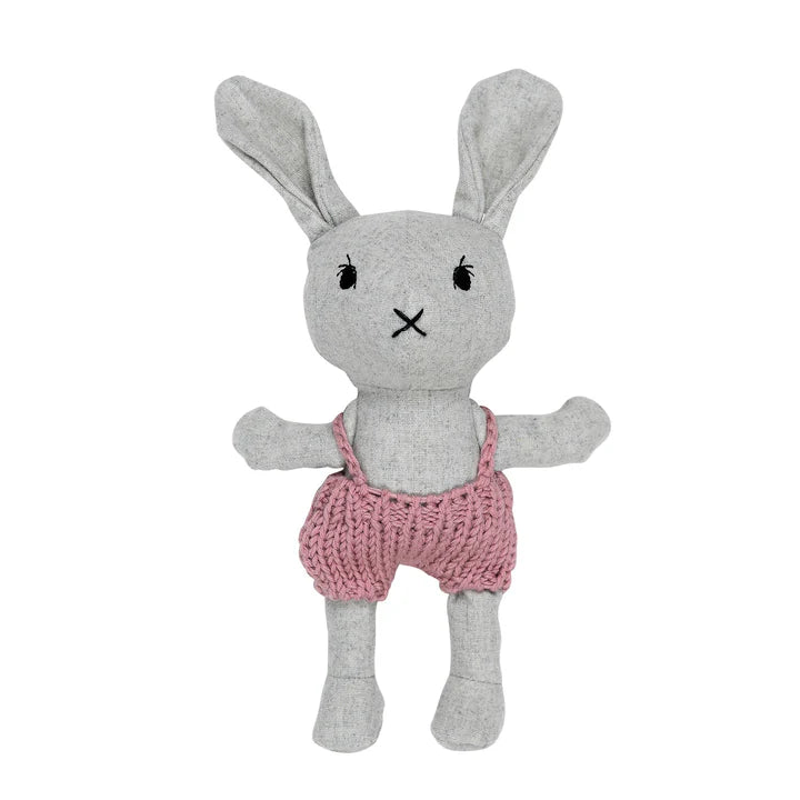 Gray plush bunny toy with pink knitted overalls on a white background