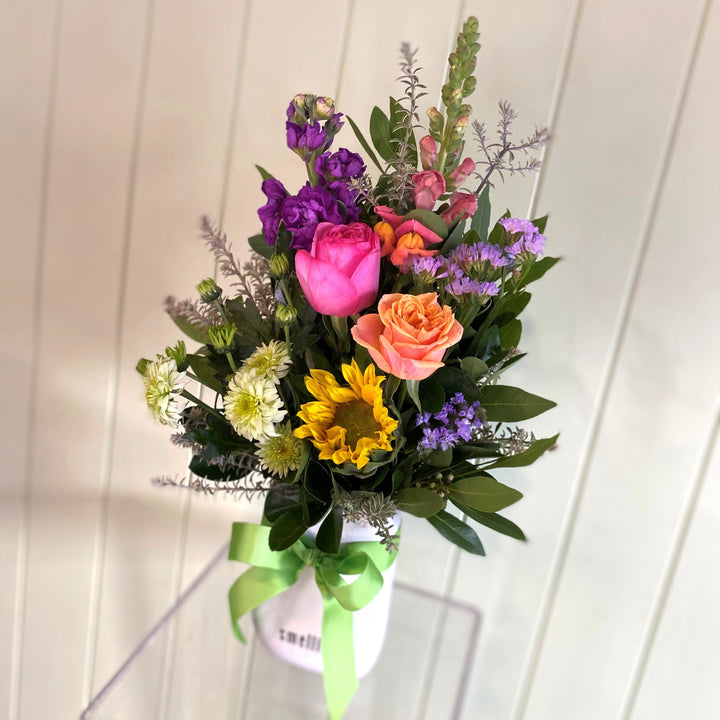 Bouquet of colorful flowers with a green ribbon against a white wooden background