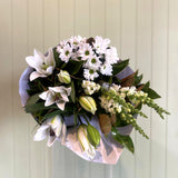 Bouquet of white and green flowers in a clear plastic wrap against a light background