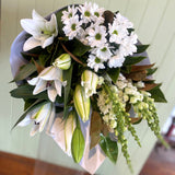 Bouquet of white and green flowers on a wooden surface with a light background