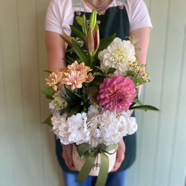 Person holding a bouquet of flowers against a white wall