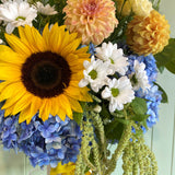 Bouquet of sunflowers, hydrangeas, and other flowers with a light green background